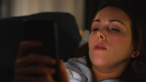 Close-Up-Of-Woman-Lying-On-Sofa-At-Home-At-Streaming-Or-Watching-Movie-Or-Show-Or-Scrolling-Internet-On-Mobile-Phone-12